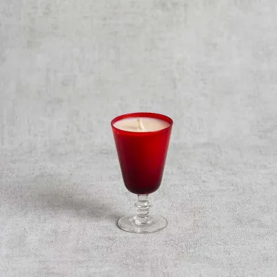 Bougie parfumée dans un verre à pied rouge élégant.